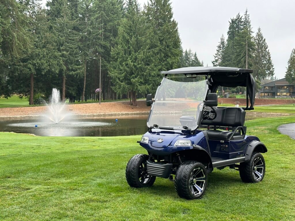 Gas vs. Electric Golf Carts: Which Is Right for You? Lifted blue golf cart parked on grass near a pond